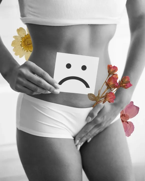 Montagem de uma pessoa segurando um cartão com rosto triste sobre o abdômen e flores